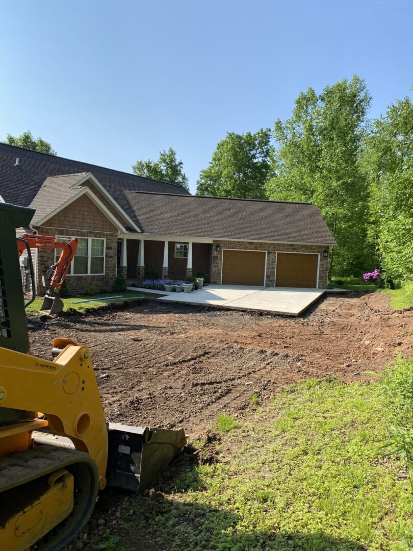 A house being built with a tractor in front of it.