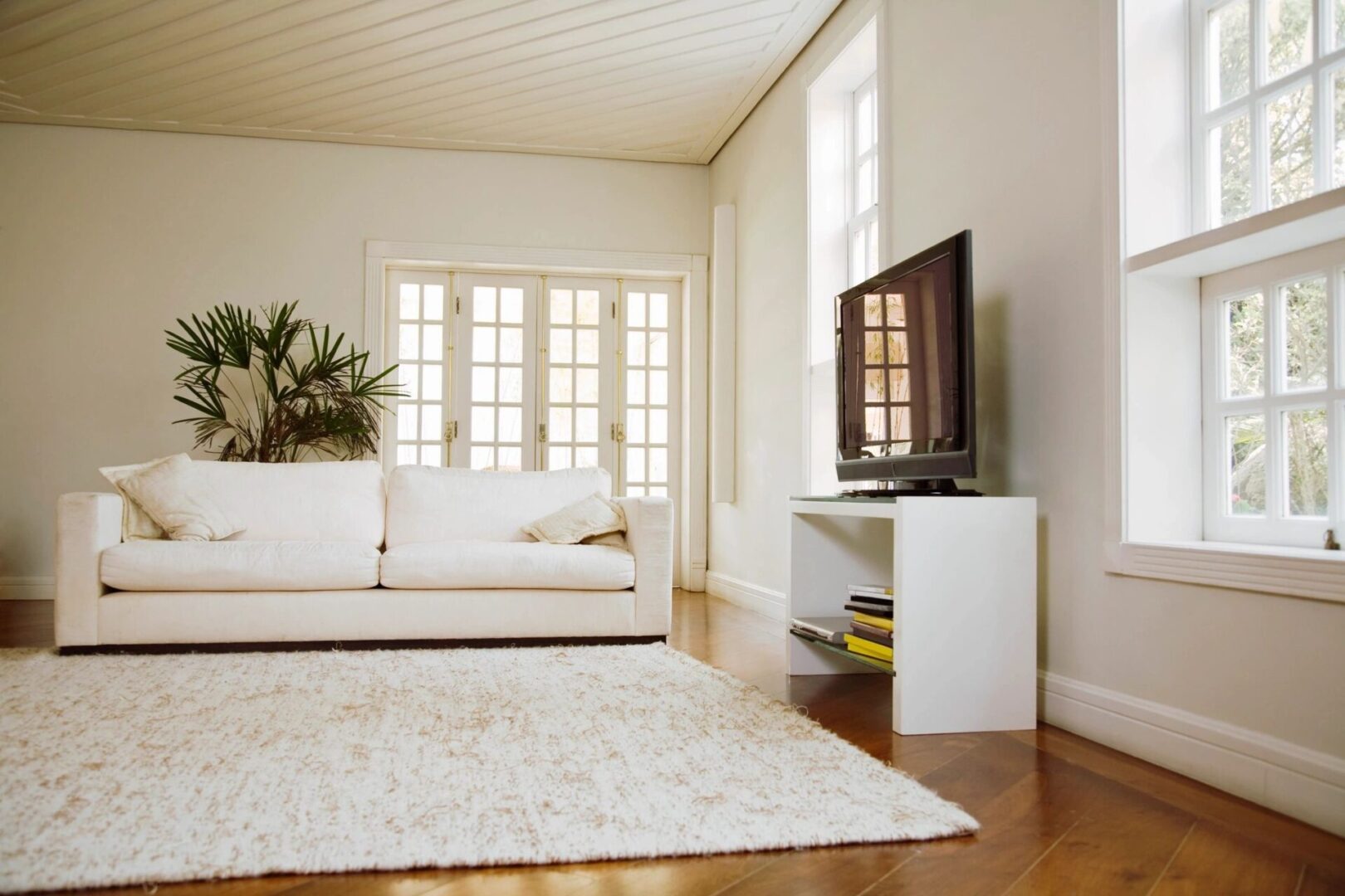 A living room with white furniture and a television.