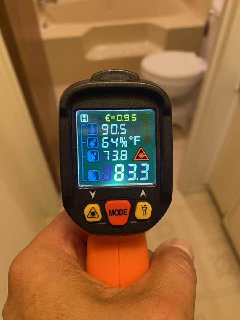 A person holding an infrared thermometer in their hand.