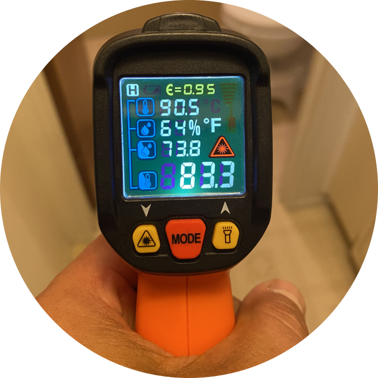 A person holding an infrared thermometer in their hand.